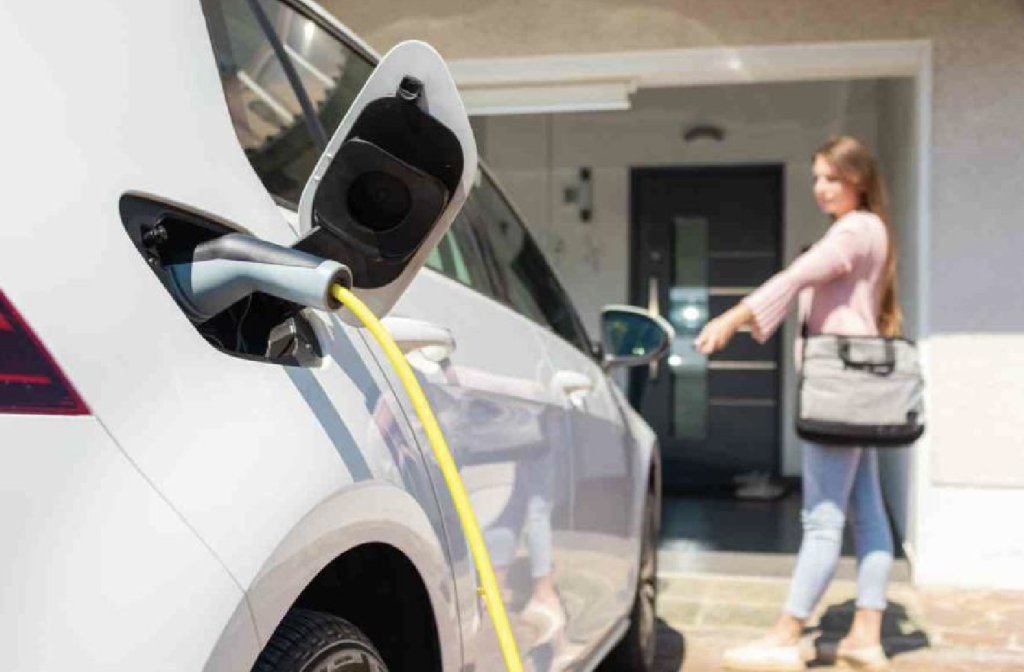 Une femme recharge un véhicule électrique à la maison